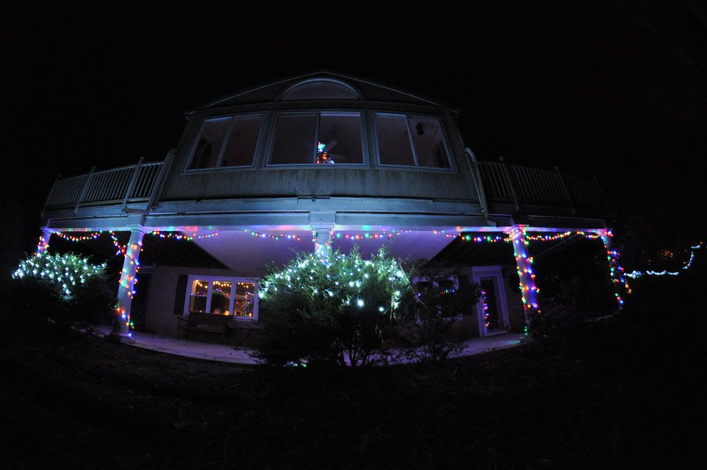 Curved roofline and porch outlined with Christmas lights at night