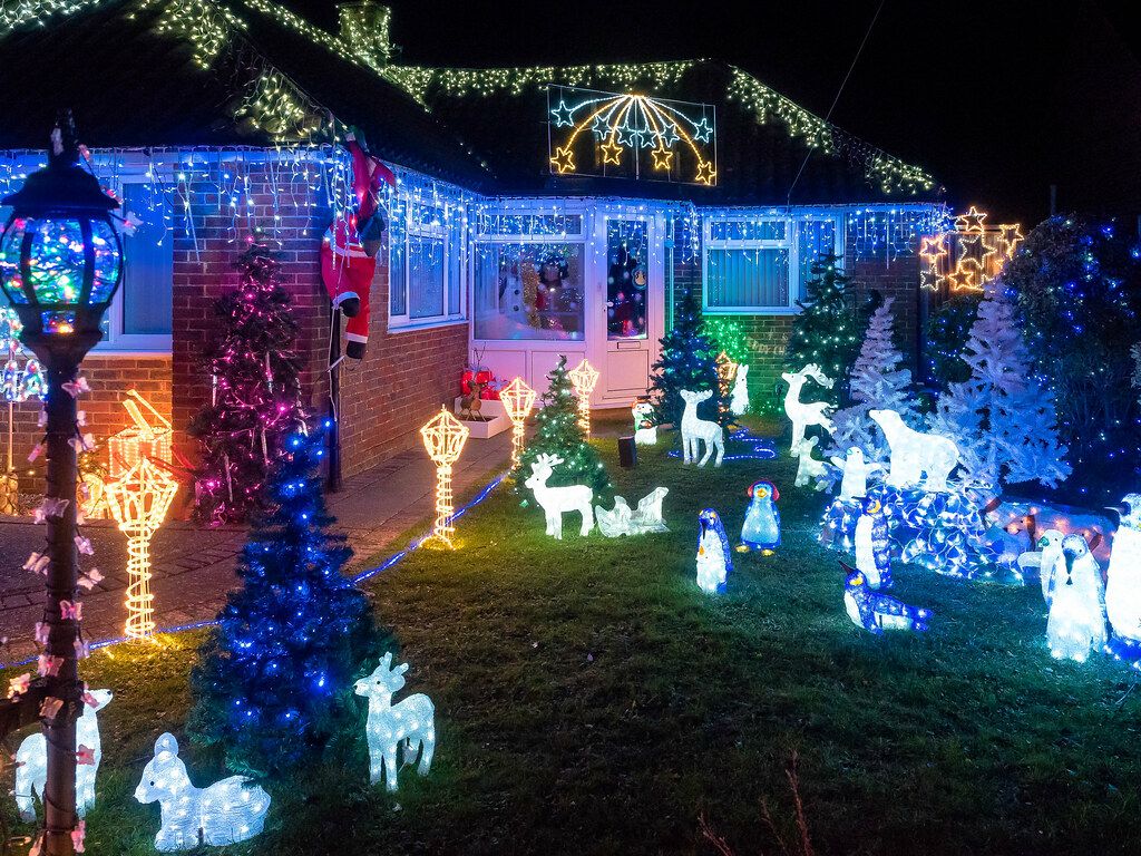 Home with colorful Christmas lights and a lit yard display at night